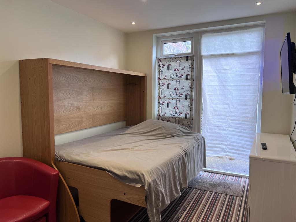 Lot: 23 - SIX-BEDROOM GUEST HOUSE - Ground floor bedroom with door to garden